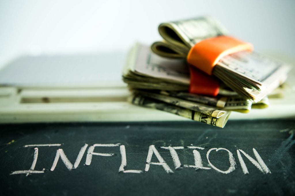 picture with the word inflation on a blackboard and money stack