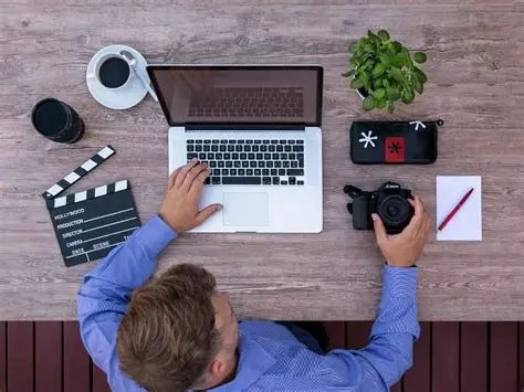 man working on his laptop next to a coffee and digital camera, referring to freelancing
