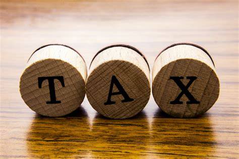 word “Tax” written by letter on individual round wooden pieces